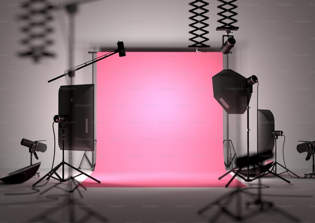 Studio fotografi dengan lampu profesional dan layar pink sebagai background.