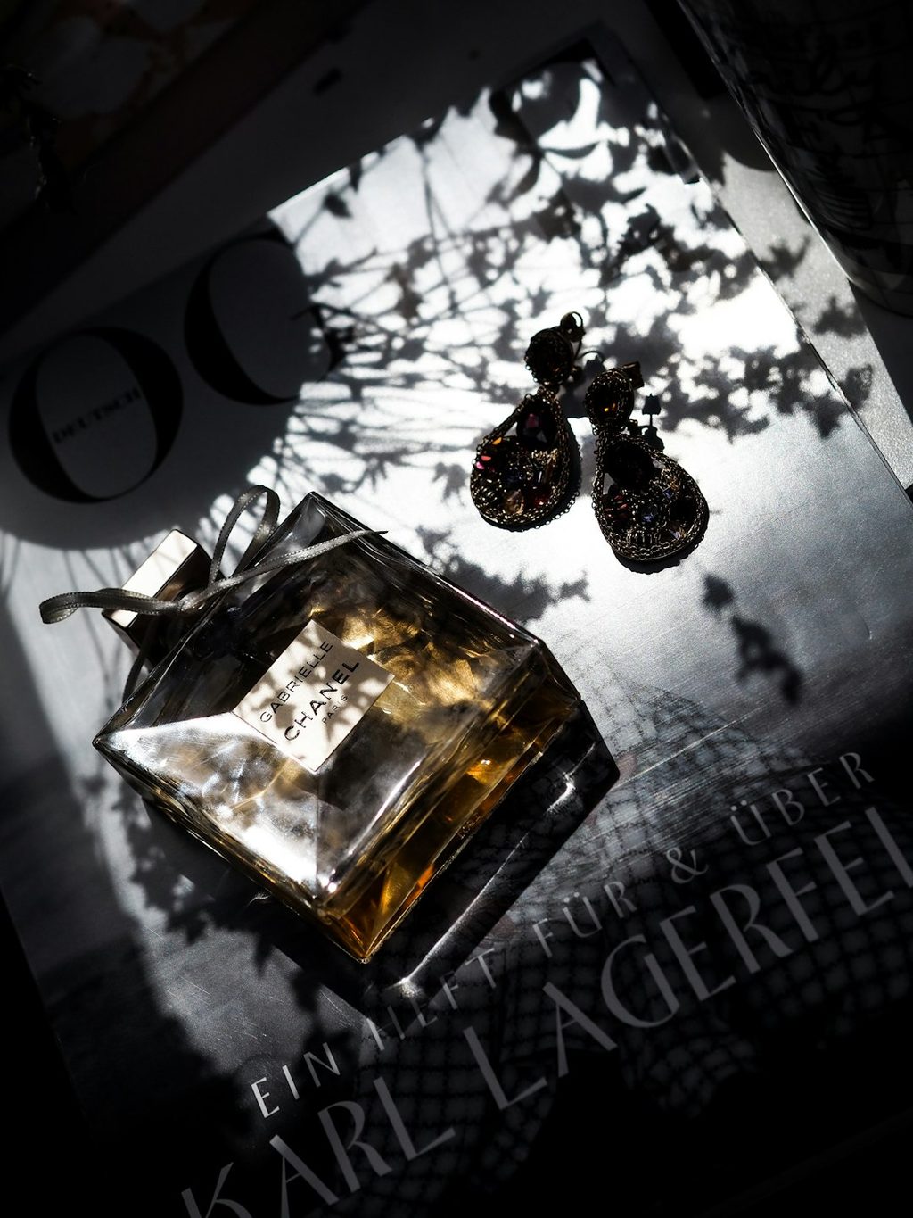 Perfume bottle with shadow on a magazine cover, black and white photography.