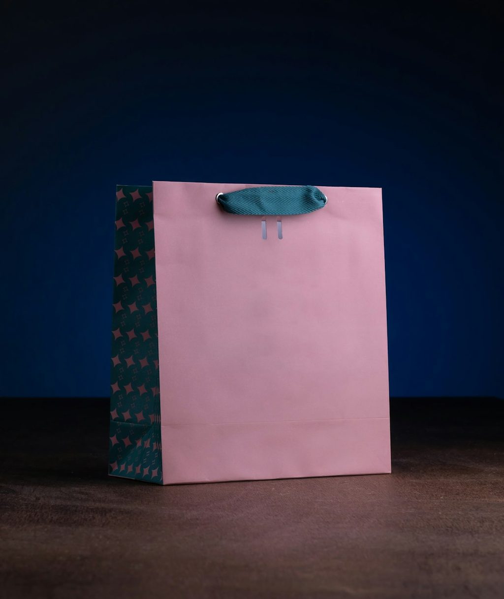 Kantong hadiah pink dengan tali hijau dan pola bintang, cocok untuk souvenir atau hadiah.