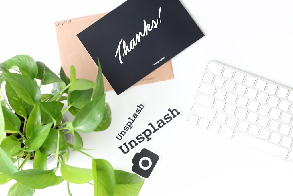 Peralatan percetakan online dengan keyboard, kartu Thanks!, dan elemen branding pada meja kerja.