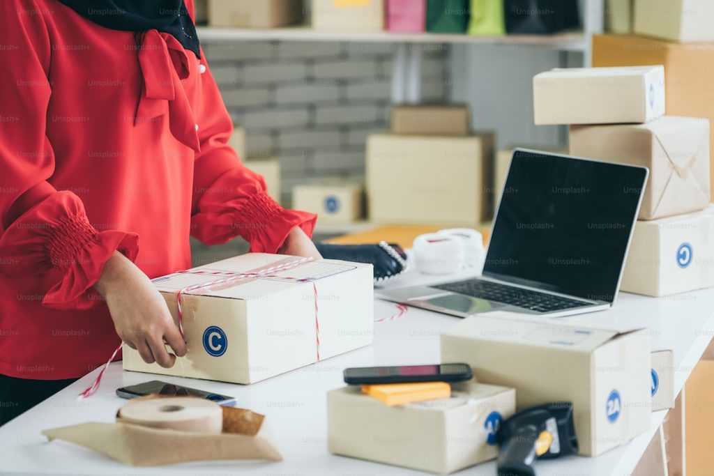 Seorang pekerja sedang memacking dan mengirim paket di Uprint.id, sebuah perusahaan percetakan online di Indonesia.