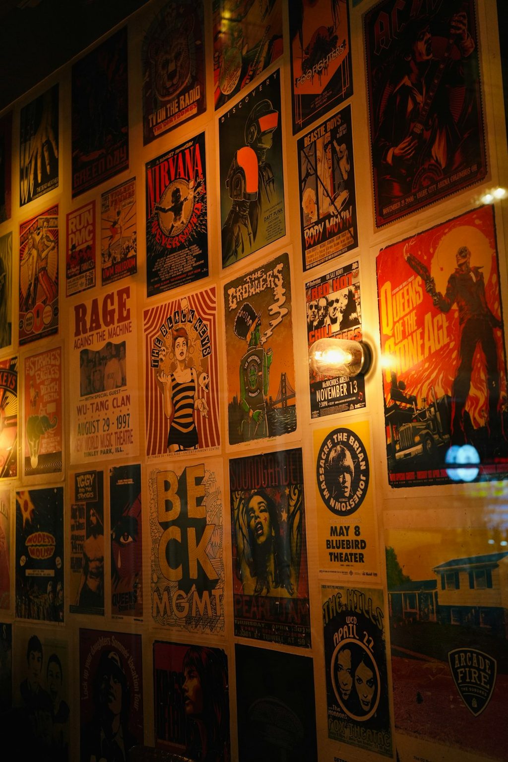 Dinding penuh poster konser musik dengan berbagai desain dan warna.