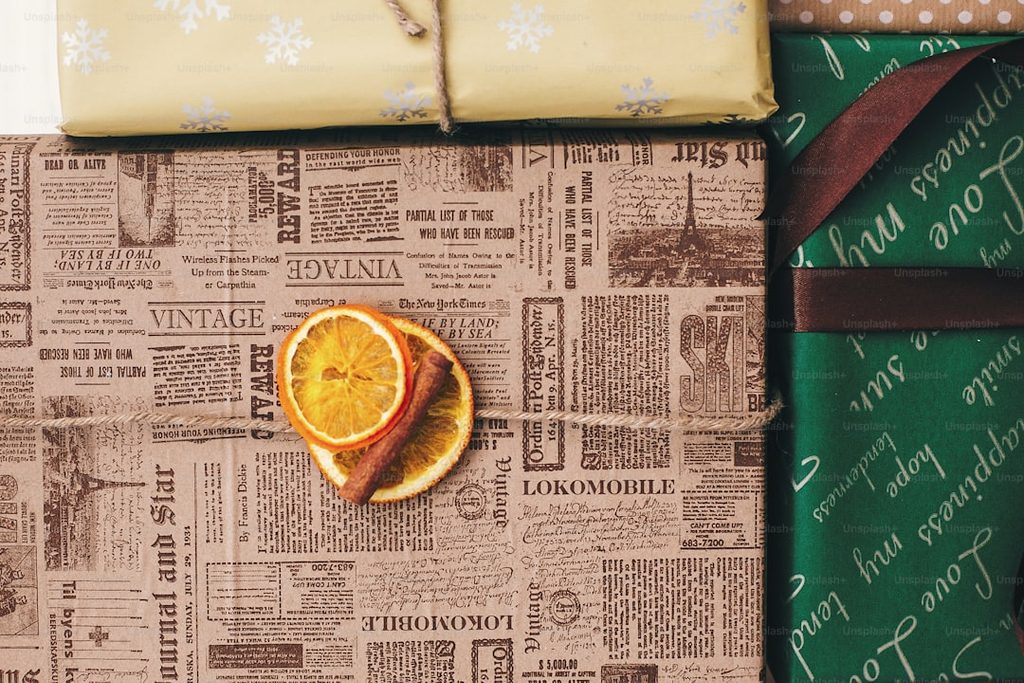 Packaging wrapped in newspaper print featuring dried orange slice for a rustic aesthetic.