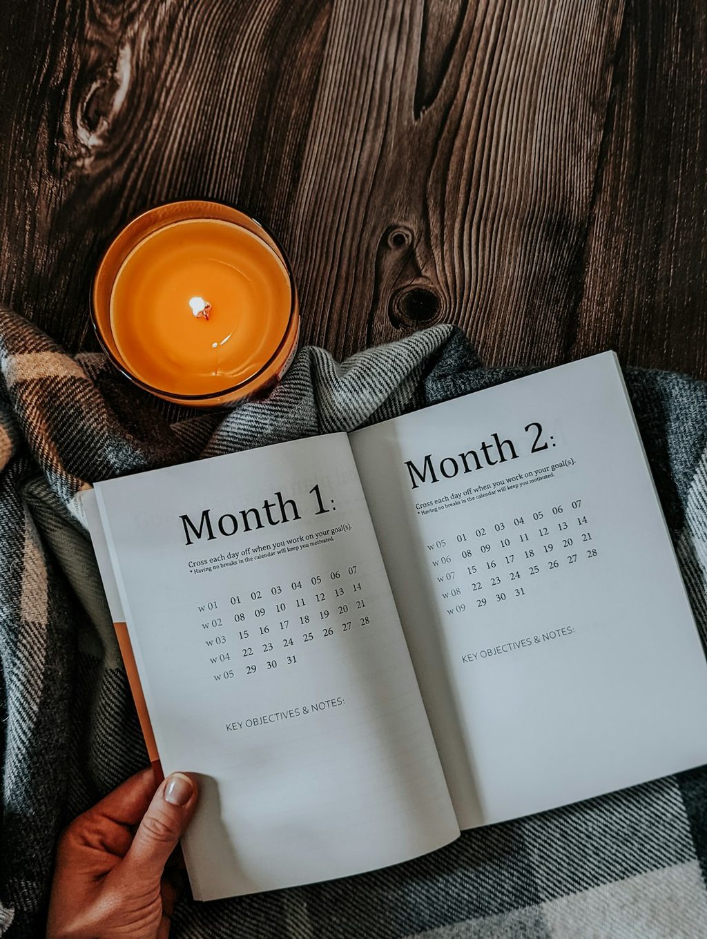 Buku kalender bulanan dengan desain minimalis, diletakkan di atas selimut coklat.