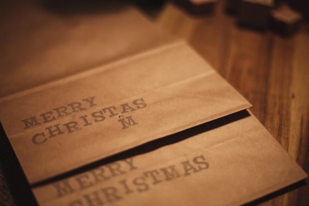 Kertas selamat datang dengan ucapan 'Merry Christmas' dalam gaya tipografi elegan.