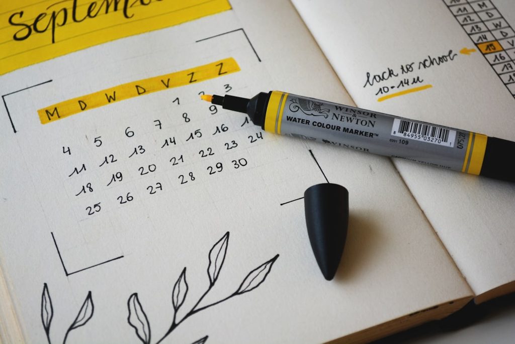 Tulisan kalender dan marker hitam di atas buku catatan