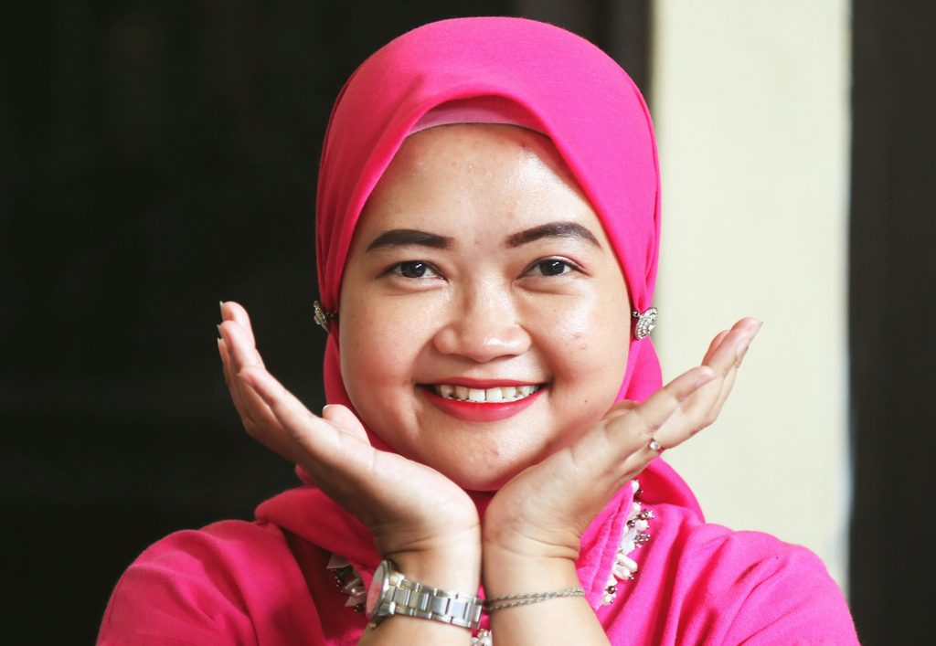 Seorang pemilik usaha wanita tersenyum puas setelah memeriksa kualitas stiker dan voucher cetak untuk bisnis online miliknya
