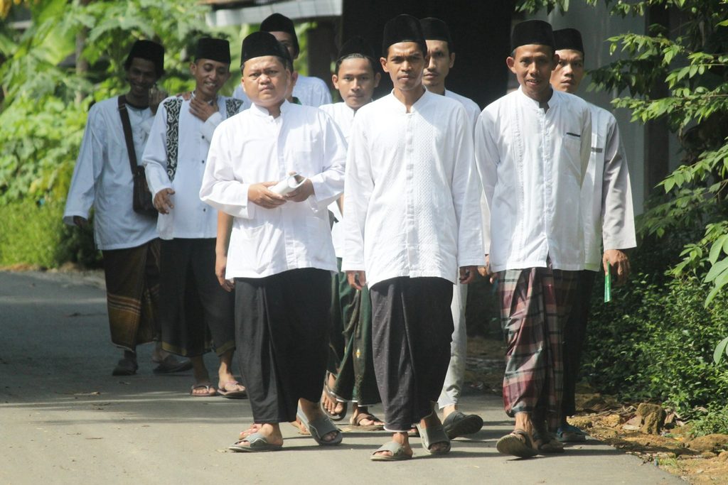 Anggota keluarga laki-laki berpose bersama mengenakan pakaian putih senada saat Lebaran