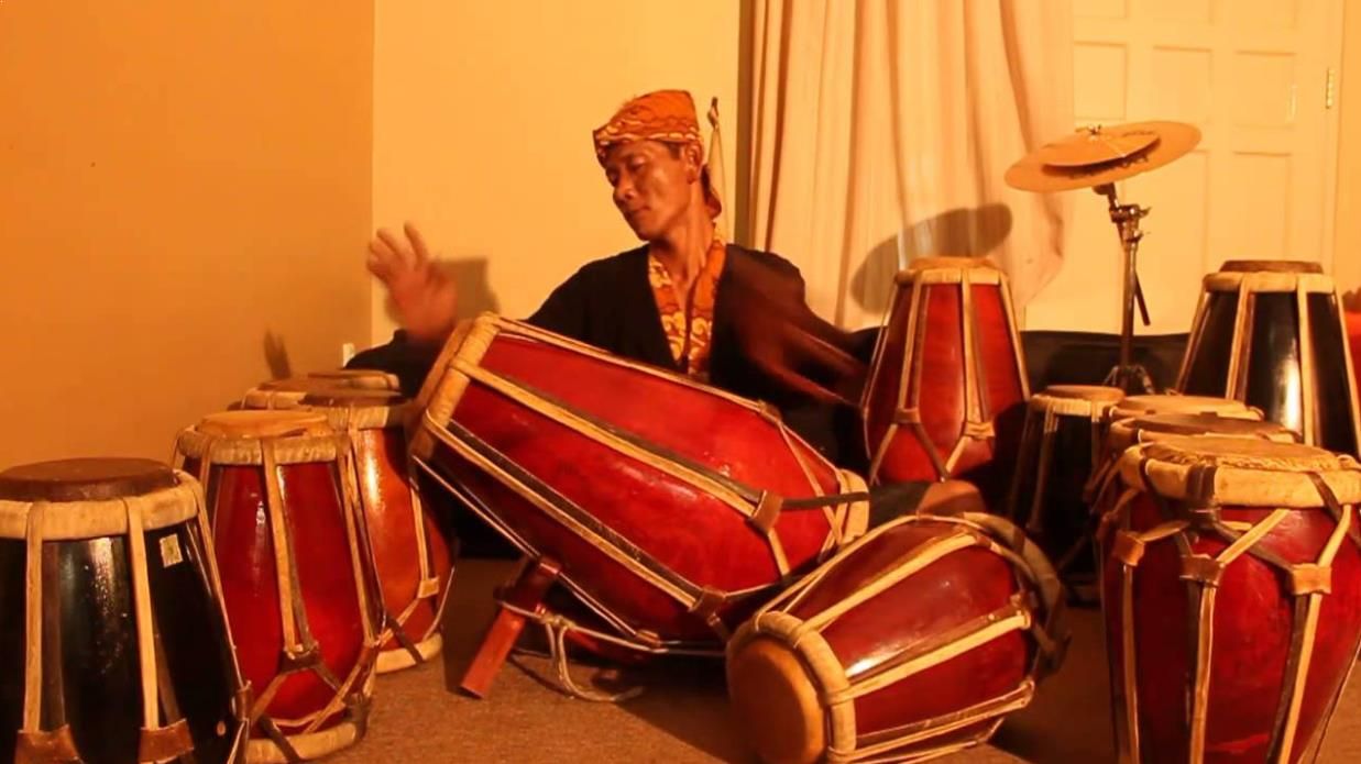 Orang memainkan alat musik tradisional di ruangan.