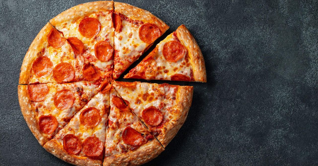Pizza pepperoni potong-potong di atas meja hitam