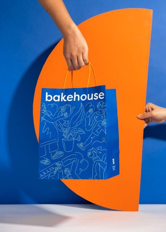 Tas belanja biru dengan logo Bakehouse dan ilustrasi kuliner
