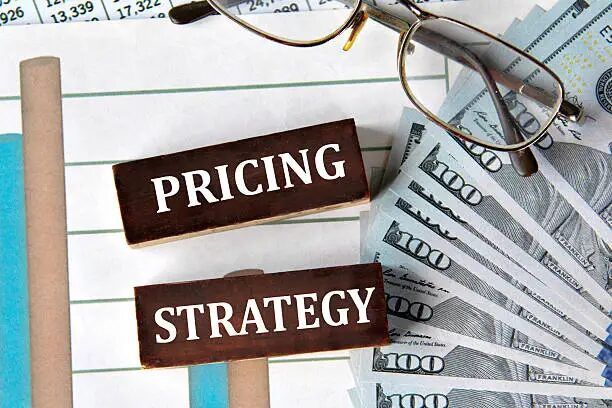 Tulisan 'Pricing Strategy' di atas lembaran kertas dengan latar uang dolar AS