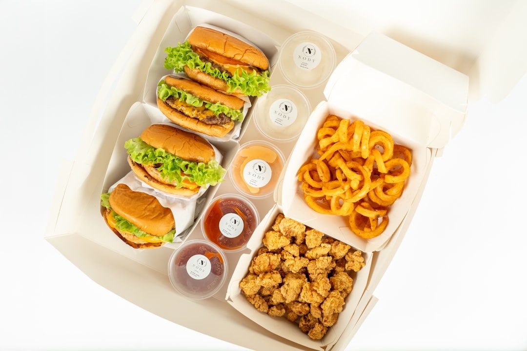 Paket makanan dengan burger, ayam goreng, dan kentang goreng dalam kemasan percetakan online.