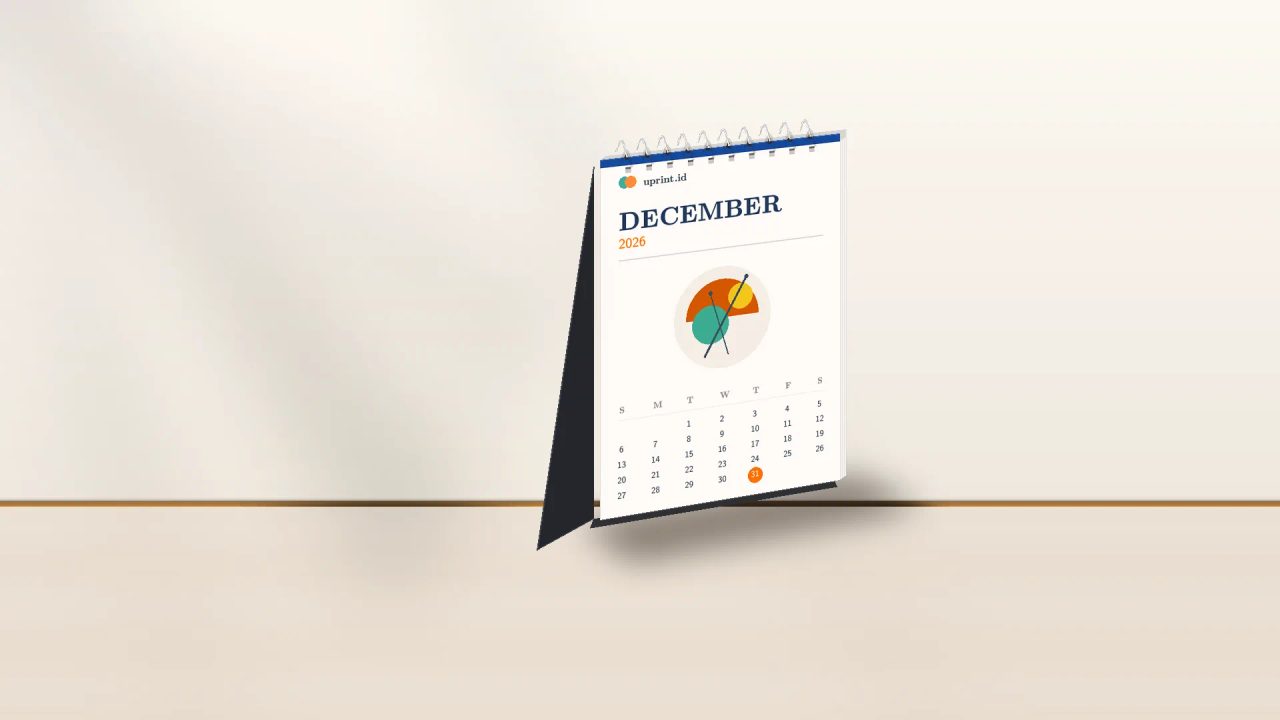 Desain kalender portrait A6 7 lembar Uprint.id berdiri rapi di atas meja kerja kayu dengan pencahayaan studio hangat.