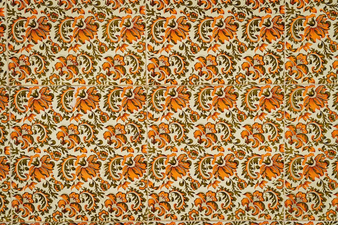 Gambar motif floral klasik dengan warna oranye dan hijau muda pada latar putih.