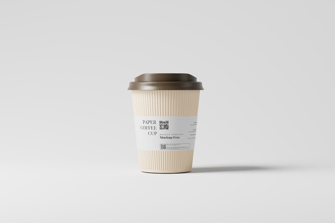 Cangkir kertas putih dengan tutup hitam dan label kopi, cocok untuk promosi percetakan online.