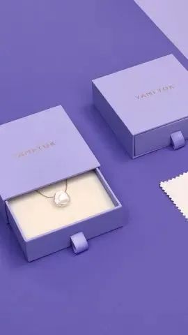 Kotak perhiasan ungu muda berfinishing matte dengan kalung di dalamnya.