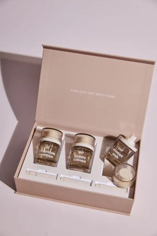 Kotak hadiah karton berisi tiga botol parfum kecil dan aksesori