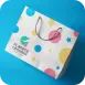 Kotak kertas hadiah dengan motif warna-warni dan permukaan mengilap di latar biru.