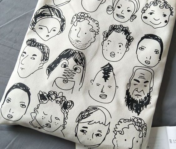 Tas kanvas putih dengan desain gambar wajah-wajah unik dan lucu.