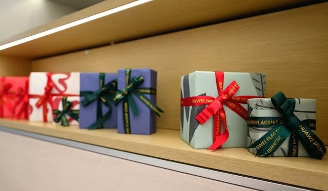 Beberapa kotak hadiah Huawei dengan tali dan banderol di rak.