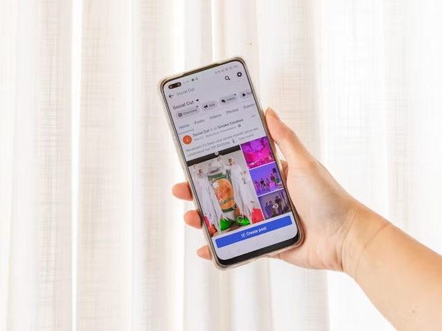 Tangan memegang smartphone menampilkan aplikasi percetakan online