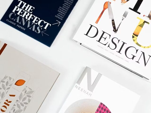 Tampak beberapa buku dan bahan percetakan berkualitas tinggi, termasuk 'The Perfect Canvas' dan 'Design'.