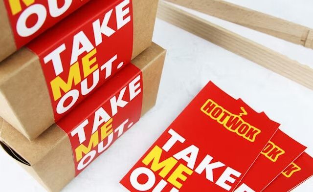 Stiker 'Take Out' dan 'Hotwok' di atas kotak kraft.