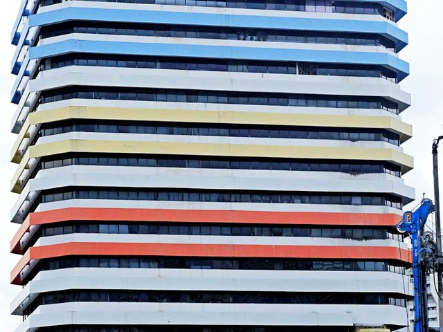 Gedung tinggi dengan lantai berwarna cerah dan detail unik pada atap.
