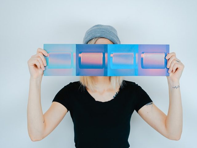 Perempuan menunjukkan contoh cetakan biru dan ungu dari aplikasi Uprint.id