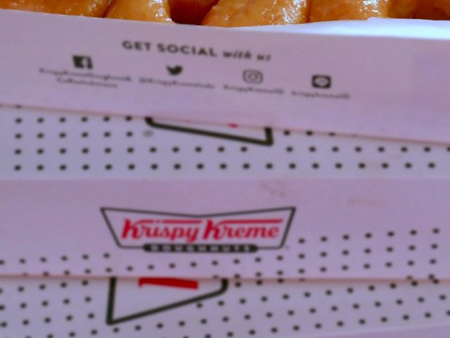 Krispy Kreme donuts arranged neatly in a box with branding.