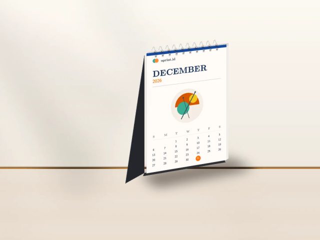 Desain kalender portrait A6 7 lembar Uprint.id berdiri rapi di atas meja kerja kayu dengan pencahayaan studio hangat.