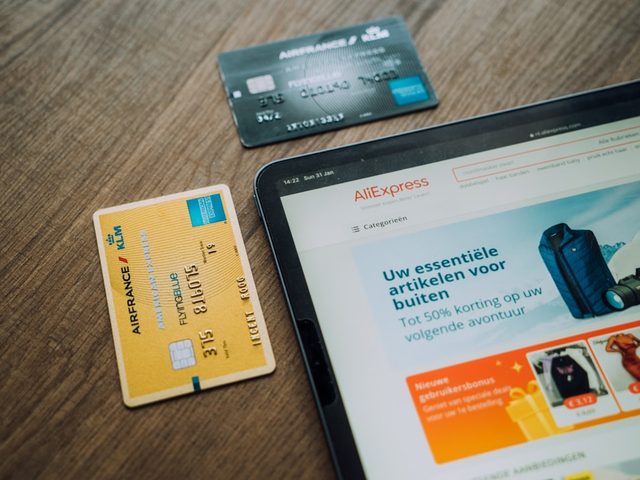Tampilan layar tablet menunjukkan produk AllExpress dengan kartu pembayaran di meja.