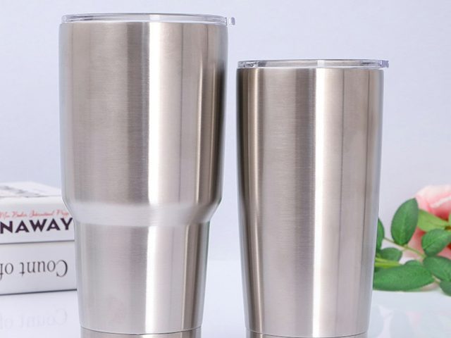 Dua gelas tumbler stainless steel berukuran berbeda dengan tutup transparan.