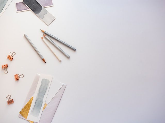Pensil, klem, dan kertas warna di atas meja putih sebagai bahan desain flyer berkualitas premium
