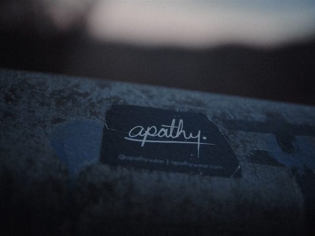 Label hitam dengan logo Apathy di atas permukaan tekstur.