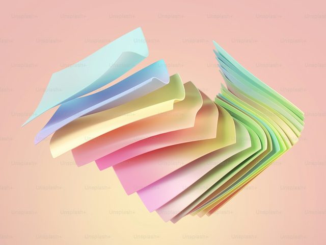 Pile of colorful papers arranged in a fan shape on a pink background.