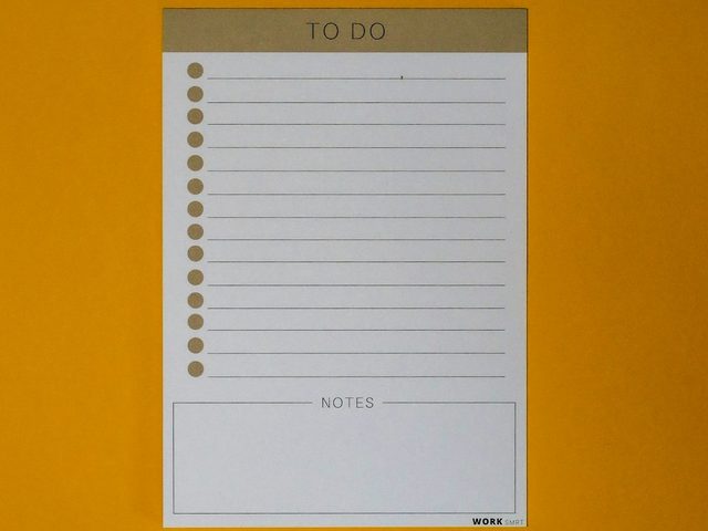 Nota to-do list putih dengan garis dan kotak catatan di atas latar kuning.