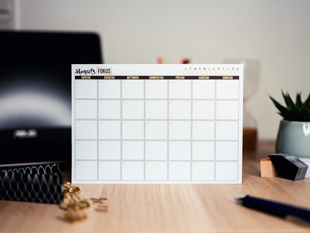 Gambar kalender digital dengan layout kosong di meja kerja.